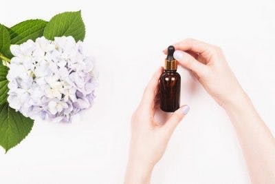 Frau, die Bernsteinflasche des Magnesiumölgeschenks für Schlaganfallpatienten hält