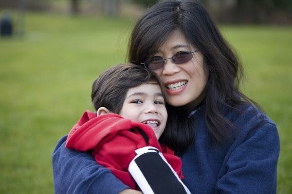 mother hugging son with acquired cerebral palsy