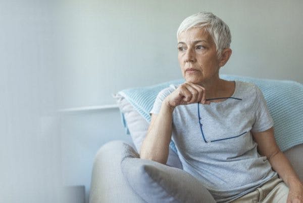 ältere Frau, die aus dem Fenster schaut, in Gedanken versunken, weil sie nach einem Schlaganfall Angst hat