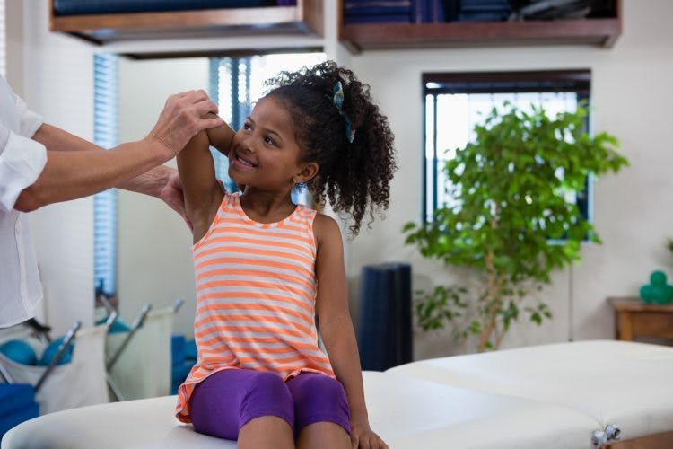 girl with cerebral palsy practicing stretches to reduce spasticity