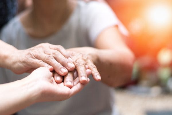 close up of doctor holding patient's hand, answering whether head injury can cause parkinson's