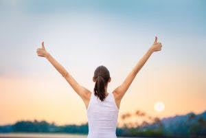 Young woman with arms in the air giving thumbs up and celebrating a small victory