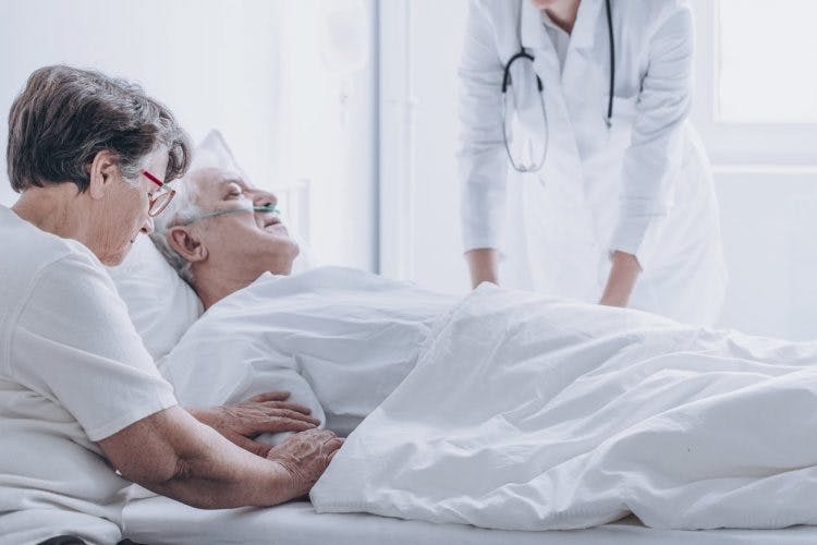 stroke patient lying in hospital bed surrounded by family members