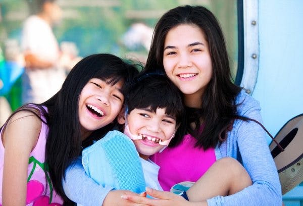 two sisters watching over brother with a type of cerebral palsy called spastic quadriplegia