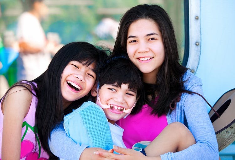 two sisters watching over brother with a type of cerebral palsy called spastic quadriplegia