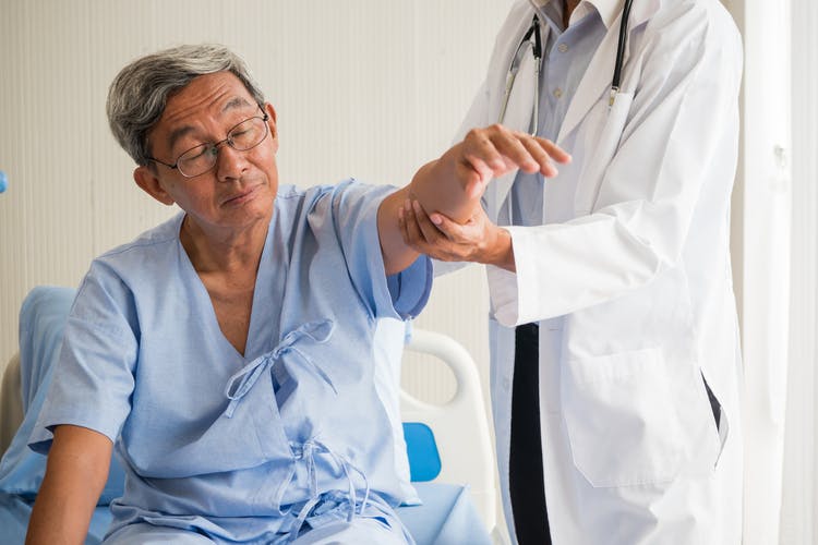 Doctor testing stroke patient's arm for learned nonuse after stroke