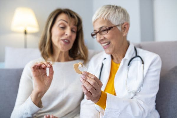 Doctor showing TBI patient hearing aids to help treat her hearing loss after head injury