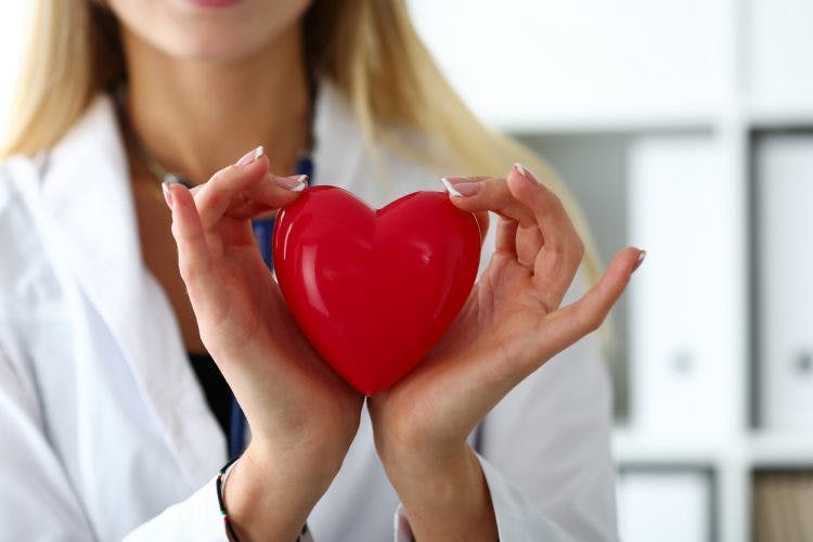 doctor holding a red heart between her hands to symbolize hand recovery