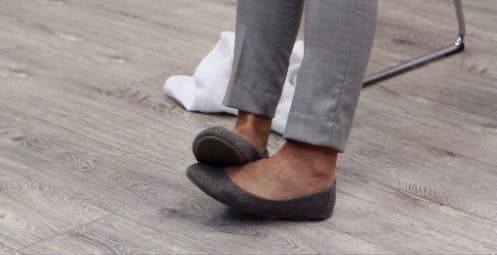 Une thérapeute se sert de son pied indemne pour aider à reposer les orteils de son pied affecté dans un exercice qui vise le pied tombant.