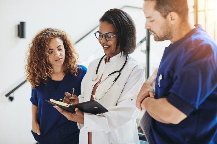 doctor in white lab coat talking over brain scans with two nurses to explain why every stroke is different