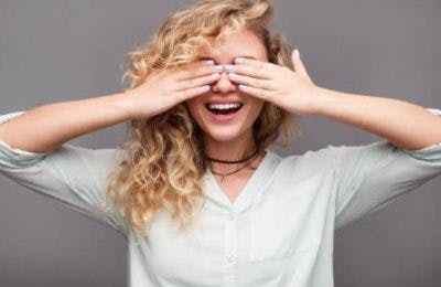 Une femme se sert des mains pour couvrir les yeux pour symboliser le principe de la thérapie par privation de la vue.
