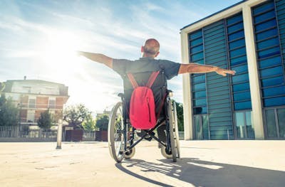 Hombre en silla de ruedas con los brazos extendidos mostrando actitud positiva