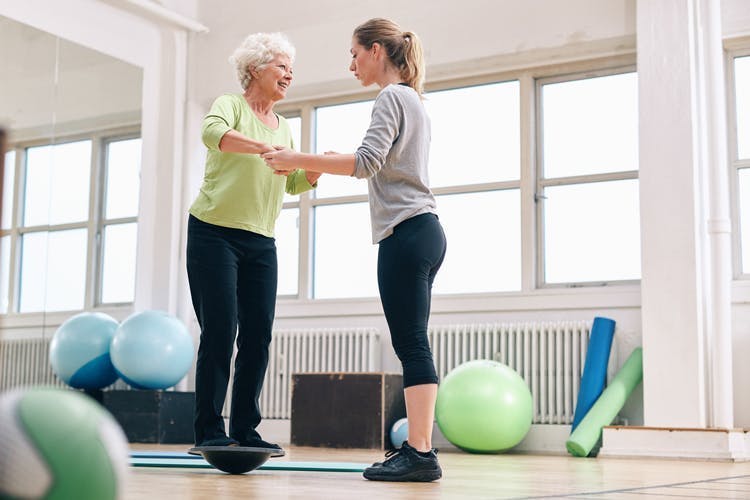 Terapeuta ayuda a equilibrar a paciente con accidente cerebrovascular durante la rehabilitación hospitalaria