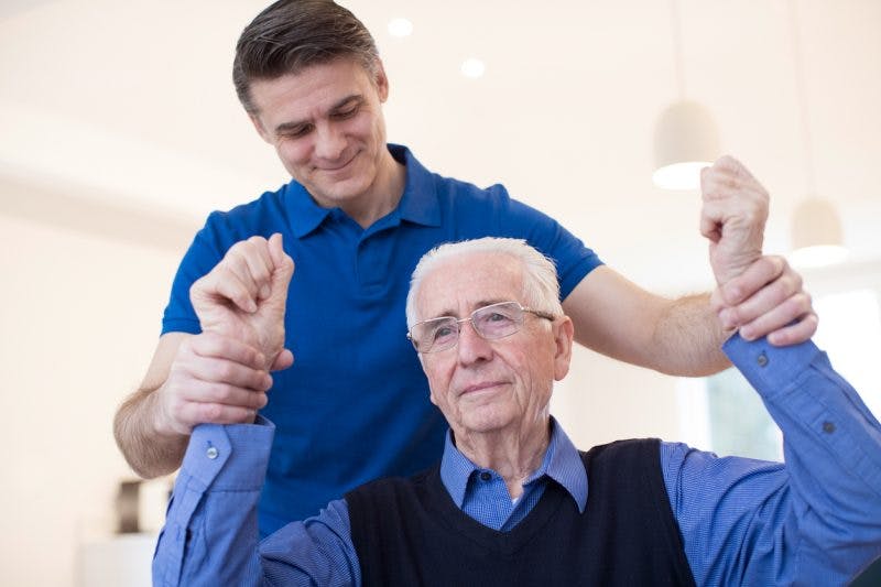 Physical therapist raising stroke patient's arms to help him overcome flaccidity after stroke