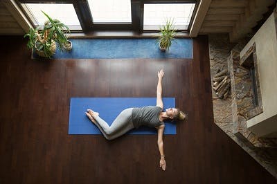 spinal cord injury patient lying on mat with knees to the left side for a full spinal rotation core exercise