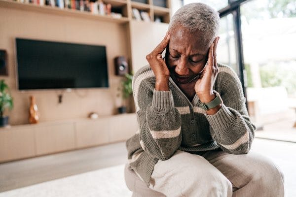 woman with hands on temples struggling with headache after brain injury