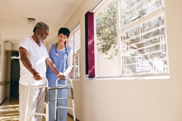 physiotherapist helping patient with hemiparesis use a walker