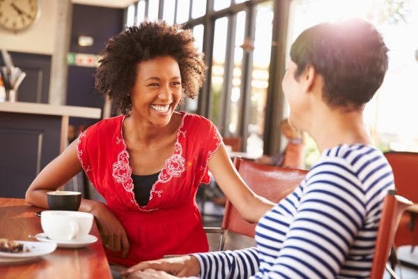 smiling woman talking to someone with brain injury in coffee shop