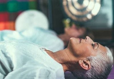 Une patiente allongée sur le dos, aux yeux fermés, fait de la pratique mentale pour envisager ses mouvements avant de les faire : ce qui aide à stimuler la cerveau et la neuroplasticité.