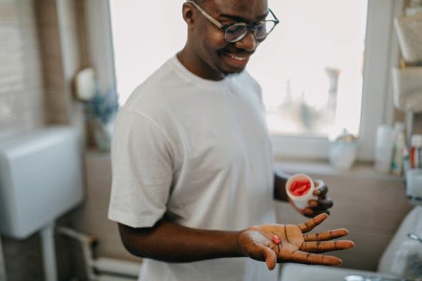 brain injury survivor smiles while holding vitamins in his hand