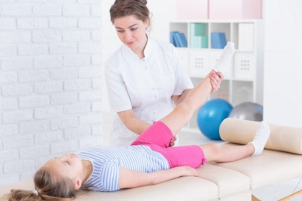 phsycial therapist helping child with cerebral palsy relax tight muscles with massage therapy
