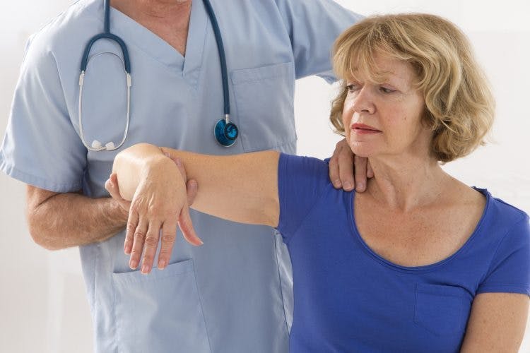 Schlaganfallpatient mit steifen Muskeln nach Schlaganfall, der mit Physiotherapeut arbeitet