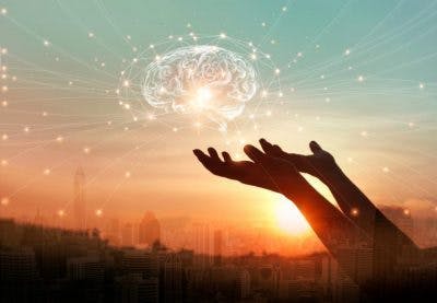 hands holding hologram of brain in front of sunset