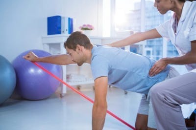 Thérapeute aidant un patient hémiplégique à faire de l'exercice dans une clinique de physiothérapie
