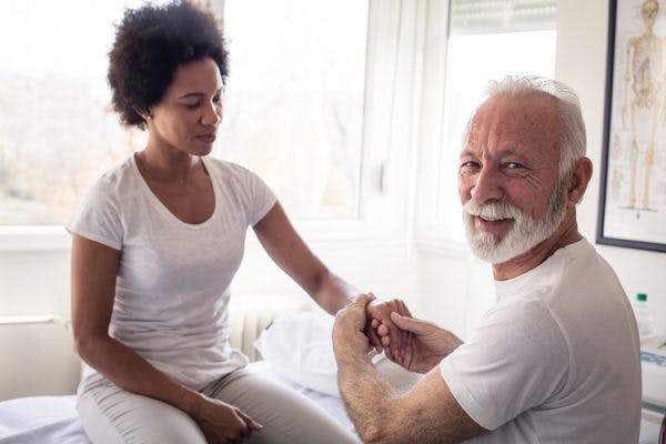 physical therapist helping survivor with a clenched hand after stroke in clinic setting