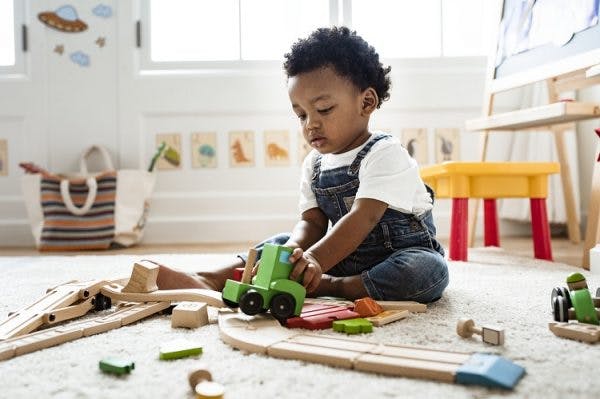 Cute little boy with cerebral palsy playing with a railroad train toy as part of play therapy