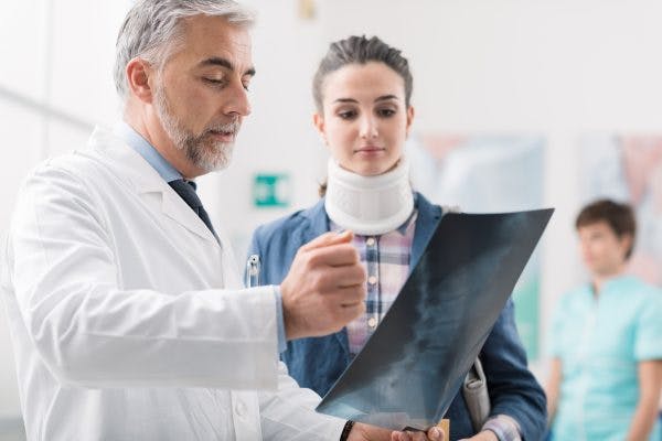 Doctor looking at female patient's x-ray explaining post-traumatic cervical dystonia to her