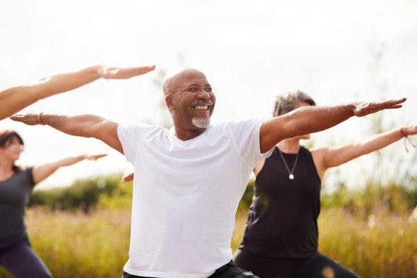 Senior man doing group yoga in park to promote a successful mini-stroke recovery
