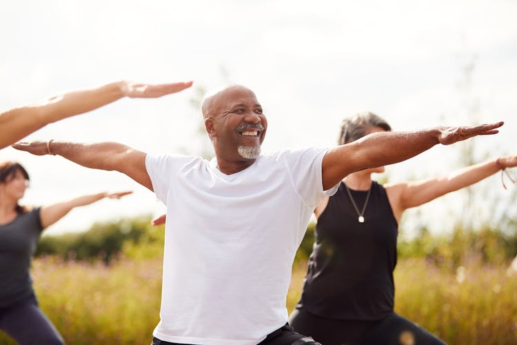 Senior man doing group yoga in park to promote a successful mini-stroke recovery