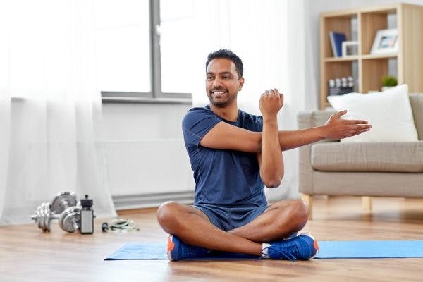 survivor sitting down on a mat practicing hand exercises for spinal cord injury