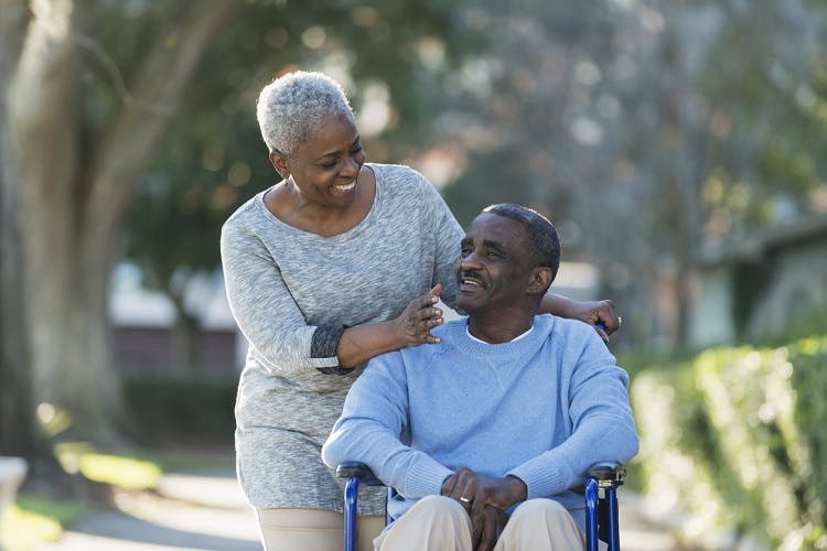 wife pushing husband with severe brain injury in wheelchair