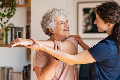 Une soignante aide une patiente à effectuer des exercices de récupération avec son bras affecté par l'AVC.