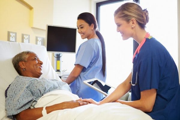 two nurses discuss speech therapy after stroke with survivor in hospital bed
