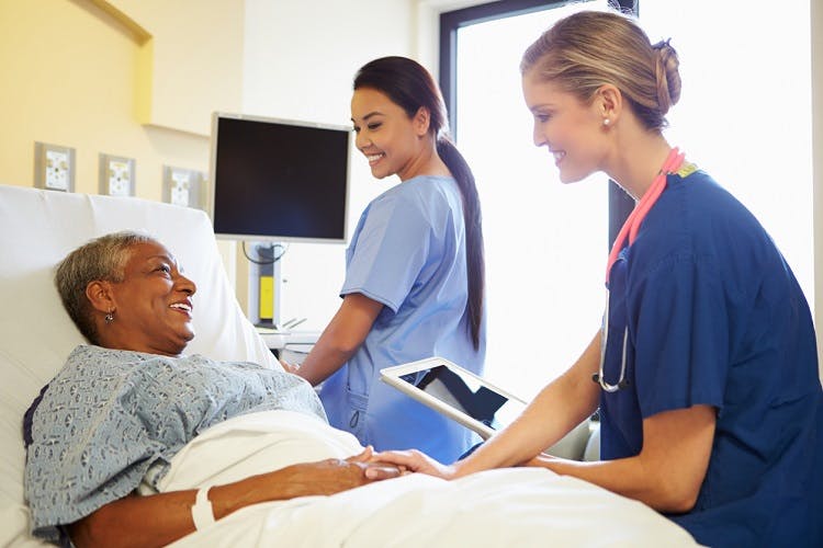 two nurses discuss speech therapy after stroke with survivor in hospital bed