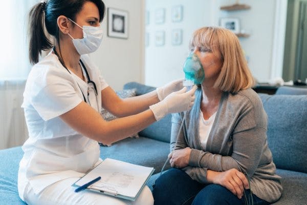 Doctor providing respiratory treatment to spinal cord injury survivor at home