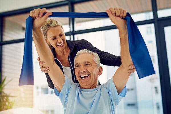 physical therapist working with spinal cord injury survivor and smiling about the signs of recovery