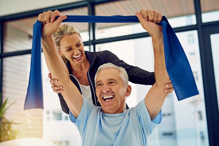 physical therapist working with spinal cord injury survivor and smiling about the signs of recovery