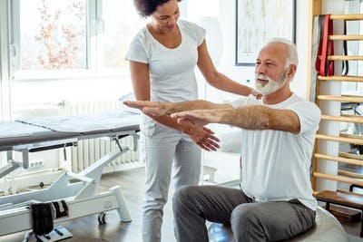 Physiotherapeut, der mit Schlaganfallpatienten in einer stationären Rehabilitationseinrichtung während der frühen Schlaganfall-Erholungszeit arbeitet