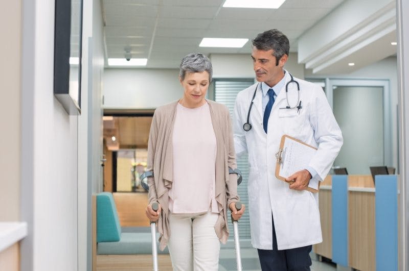 doctor escorting stroke patient out of hospital after stroke recovery plateau