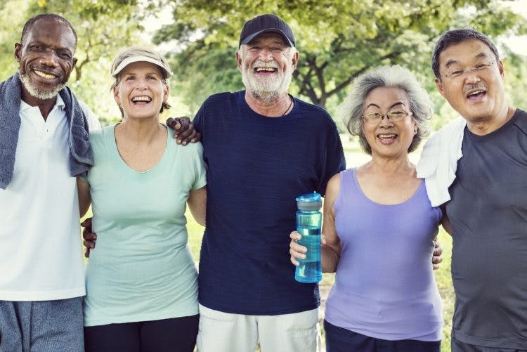 smiling senior friends with arms around each other after exercising with massed practice