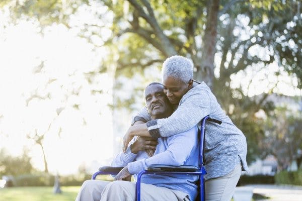 woman comforting man in wheelchair who experienced seizures after head injury