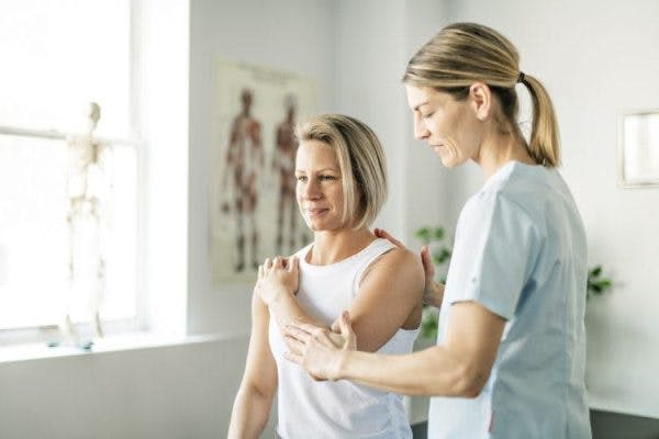 therapist adjusting survivor's arm to help with dystonia after brain injury