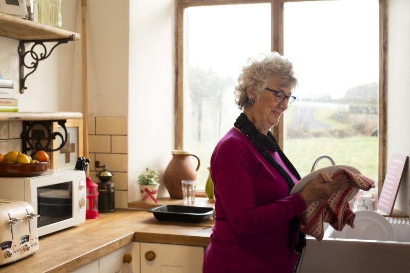 senior woman drying dishes and relearning the activities of daily living after TBI