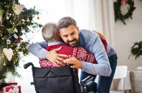 Un fils embrasse son père, qui est aussi un survivant d'AVC, ce qui symbolise le thème de cet article : comment soigner les survivants d'AVC au domicile.