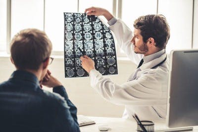 Un médecin montre à son patient une IRM indiquant la location de l'AVC, qui implique directement les troubles de la parole emportés par l'AVC.