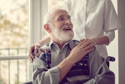 Un survivant d'AVC sur un fauteuil roulant vous lance un sourire, tout en gardant sa pensée sur les aspects positive afin qu'il puisse exploiter pleinement ses capacités pendant la récupération.
